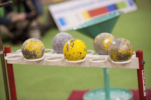 Reihe von Kugeln in verschiedenen Farben und Designs auf einem Halter für Sportgeräte in einer Trainingsumgebung.