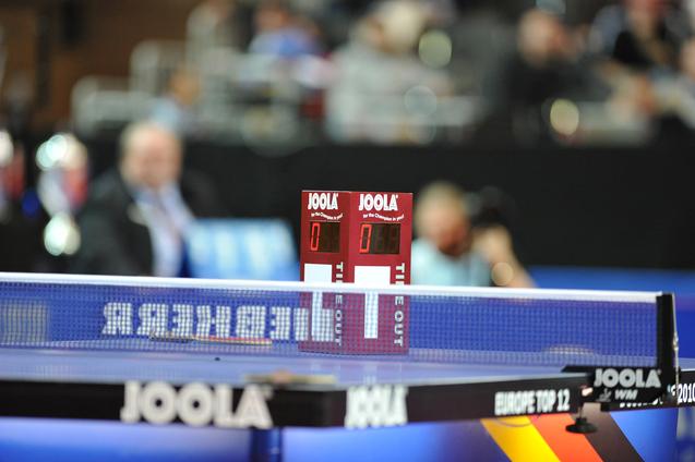 Tischtennis-Equipment mit digitalen Punkteständen 0:0 auf einer blauumrandeten Tischtennisplatte.